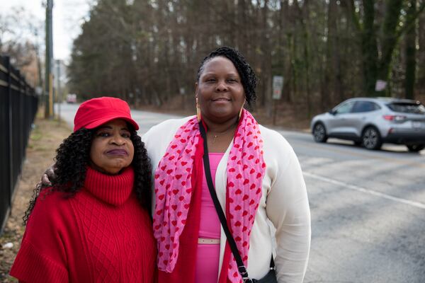 South Atlanta residents Joyce Smith (left) and Coreen Dent (right) stand for a portrait along Browns Mill Road as cars zip by on Feb. 14. (Riley Bunch/AJC)