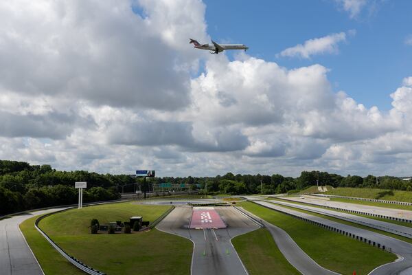 A plane flies over the track at the Porsche Experience Center in Atlanta on May 13, 2025. (Arvin Temkar/AJC)
