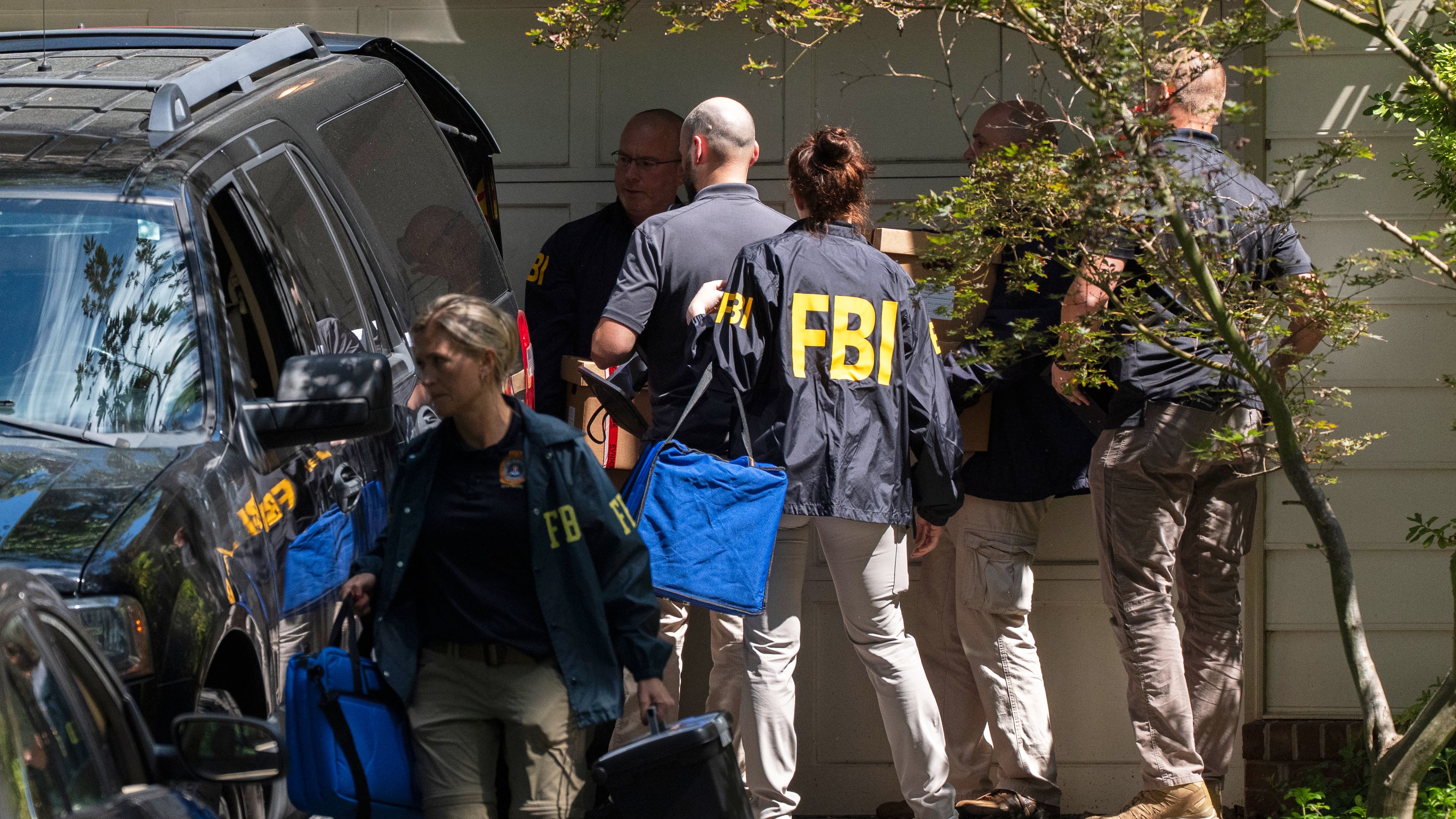FBI agents carry bags and boxes out of former national security adviser John Bolton's house Friday, Aug. 22, 2025, in Bethesda, Md. (AP Photo/Manuel Balce Ceneta)