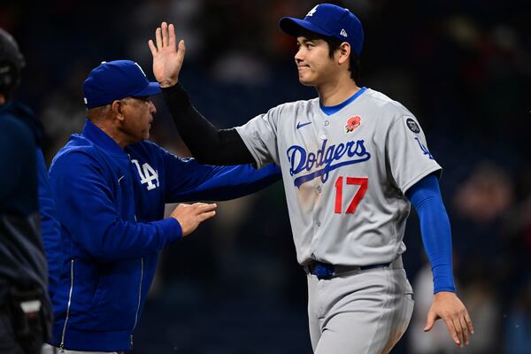 Los Angeles Dodgers' Shohei Ohtani (17) is congratulated by manager Dave Roberts, left, after the team defeated the Cleveland Guardians in a baseball game, Monday, May 26, 2025, in Cleveland. (AP Photo/David Dermer)
