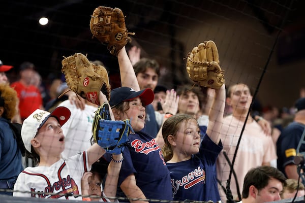 Fans hold out their gloves hoping for a ball during the seventh inning of a baseball game between the Atlanta Braves and the Cincinnati Reds, Tuesday, May 6, 2025, in Atlanta. (AP Photo/Butch Dill)