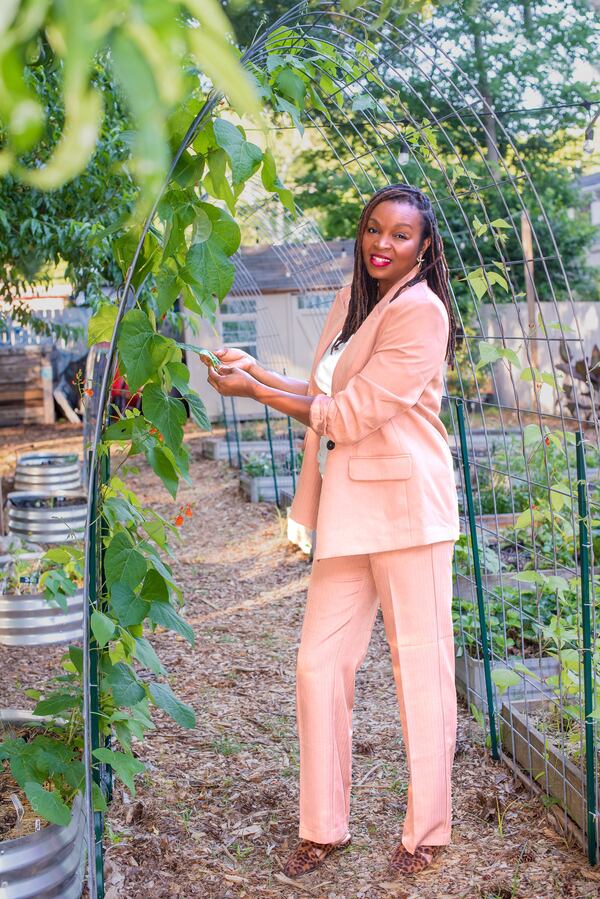 Woman stands in garden in pink suit smiling at camera from distance