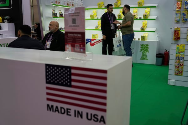 A worker chats with a visitor at the booth for Exotica Freshener Co, a U.S. company selling fresheners, at the 137th Canton Fair in Guangzhou in southern China's Guangdong province, Tuesday, April 15, 2025. (AP Photo/Ng Han Guan)