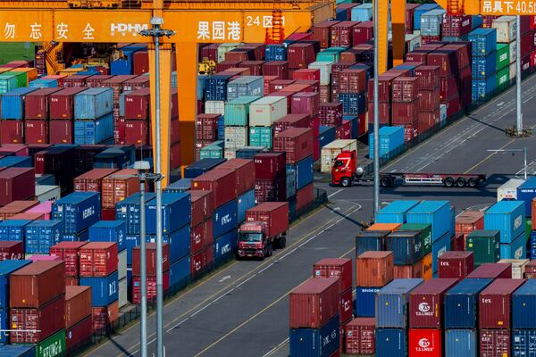 Trucks move amid containers stacked at a container terminal port on the Yangtze River in southwest China's Chongqing Municipality on Sunday, April 20, 2025. (Chinatopix Via AP)