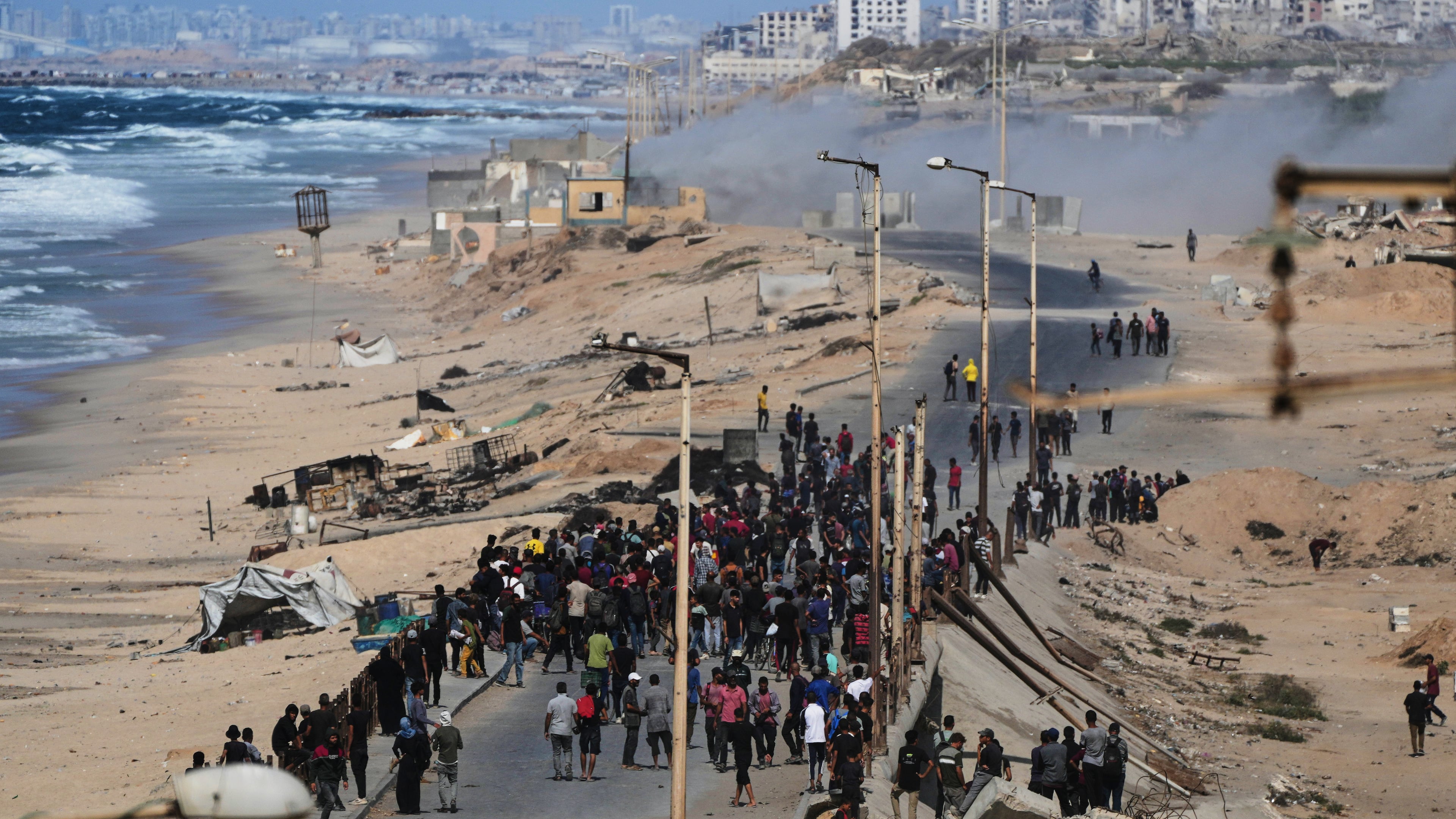 Displaced Palestinians gather on the coastal road near Wadi Gaza after the announcement that Israel and Hamas had agreed to the first phase of a peace plan to pause the fighting, as Israeli tanks block the road leading to Gaza City, in the central Gaza Strip, Thursday, Oct. 9, 2025. (AP Photo/Abdel Kareem Hana)