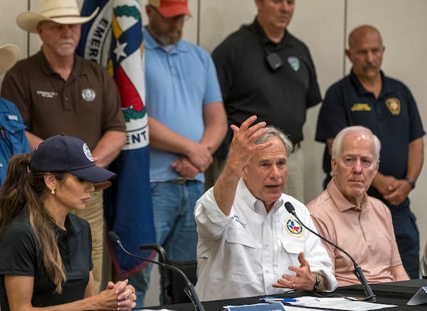 Texas Gov. Greg Abbott, center, speaks to media during a press conference as Homeland Security Secretary Kristi Noem, left, and Sen. John Cornyn listen, after recent flooding along the Guadalupe River during a press conference on Saturday, July 5, 2025, in Kerrville, Texas. (AP Photo/Rodolfo Gonzalez)