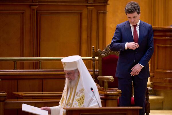 Romania’s newly elected president Nicusor Dan makes the sign of the cross as Patriarch Daniel, the head of Romania's orthodox church, finishes reading a blessing during a swearing in ceremony for the country's new president at the parliament in Bucharest, Romania, Monday, May 26, 2025. (AP Photo/Vadim Ghirda)