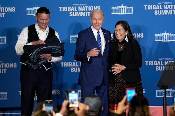 FILE - Interior Secretary Deb Haaland, right, and Bryan Newland, Assistant Secretary for Indian Affairs at the Department of the Interior, left, present President Joe Biden with an Eighth Generation blanket from a tribally-owned business, embroidered with "Joe Biden Champion for Indian Country," at the 2024 White House Tribal Nations Summit at the Department of the Interior in Washington, Dec. 9, 2024. (AP Photo/Susan Walsh, File)