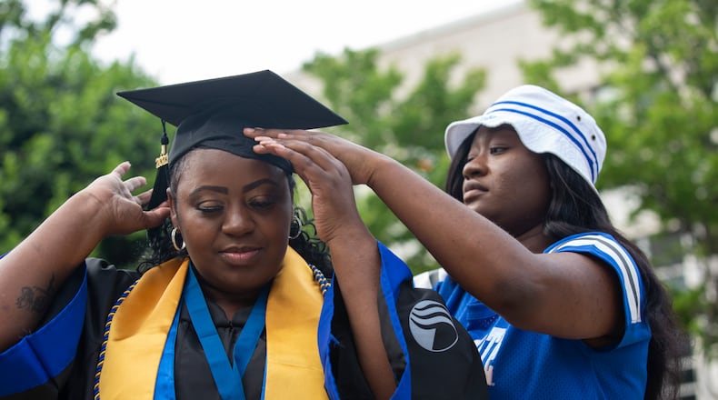 Latonya Young’s friend Essence Johnson helps her with her cap and gown at Georgia State University’s student center in downtown Atlanta, Georgia, on April 29, 2021. Young, a 44-year-old mother of three, will finally graduate from Georgia State University after numerous breaks in her education journey due to hardships. (Rebecca Wright for The Atlanta Journal-Constitution)