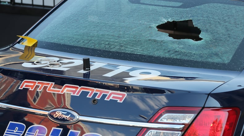An Atlanta police car with broken windows and a bullet hole in the windshield sits on Pryor Street in downtown Atlanta where police say a woman who was in custody began shooting at officers from the back seat of the patrol car Thursday evening April 30, 2015. The suspect, who police say they found in a stolen car, died after being transported to the hospital. Ben Gray / bgray@ajc.com