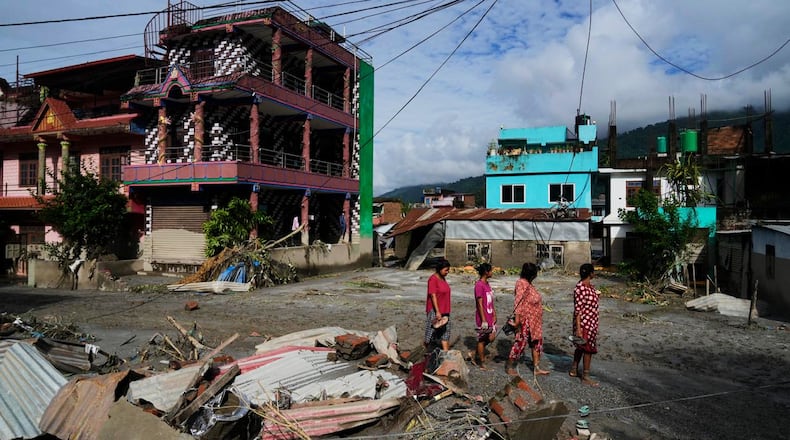 People walk past damage in the aftermath of flash floods in Devighat in the Nuwakot district in Nepal, Thursday, Aug 27, 2026. (AP Photo/Niranjan Shrestha)