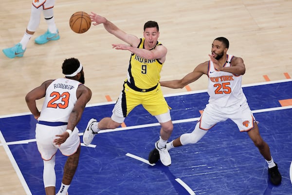 Indiana Pacers guard T.J. McConnell (9) passes the ball against New York Knicks center Mitchell Robinson (23) and forward Mikal Bridges (25) during the fourth quarter of Game 2 of the NBA basketball Eastern Conference final, Friday, May 23, 2025, in New York. (AP Photo/Adam Hunger)