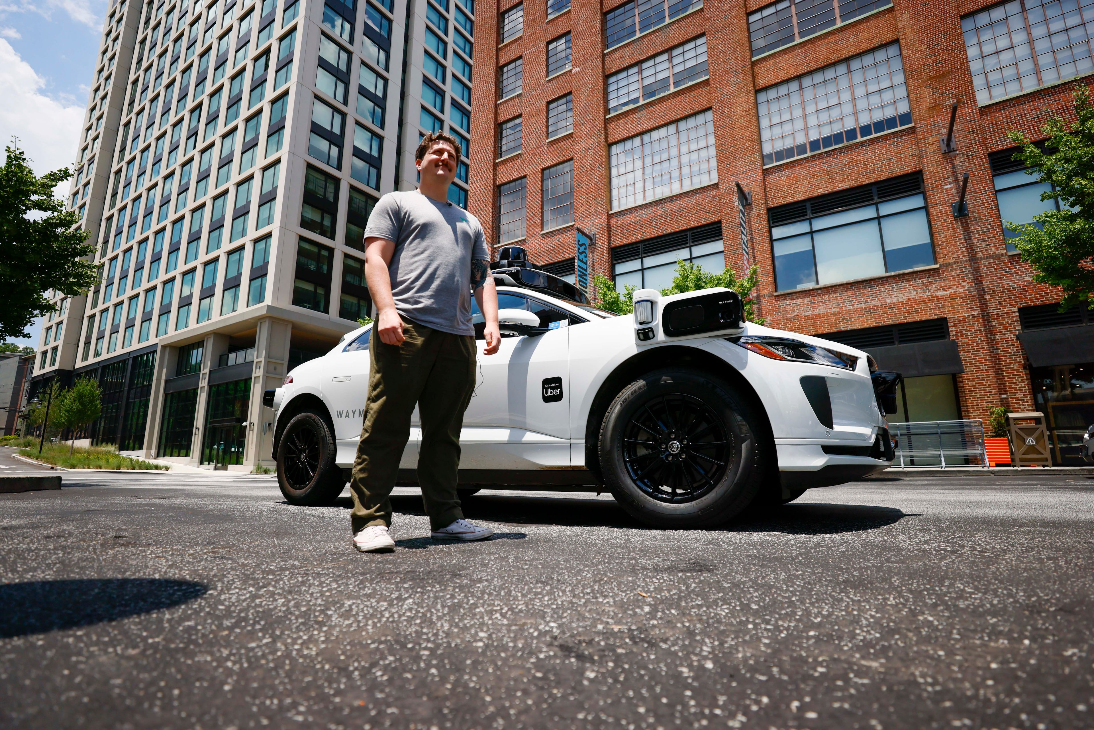Ethan Teicher, public relations manager with Waymo, poses on the side of one of the self-driving Waymo vehicles at Ponce City Market in Atlanta on Monday, June 23, 2025.
(Miguel Martinez/ AJC)
