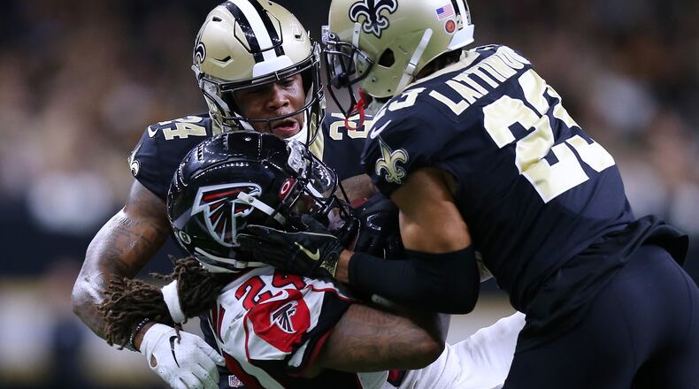 Falcons running back Devonta Freeman is tackled by the Saints' Marshon Lattimore (right) and Vonn Bell during the first half Nov. 10, 2019, at the Mercedes Benz Superdome in New Orleans.