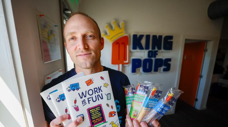 Steve Carse, co-founder of King of Pops, is pictured alongside his newly published book, "Work is Fun," as he holds a variety of pops at the company’s headquarters in Atlanta on Thursday, March 6, 2025. The company is marking its 15th anniversary. (Miguel Martinez/AJC)