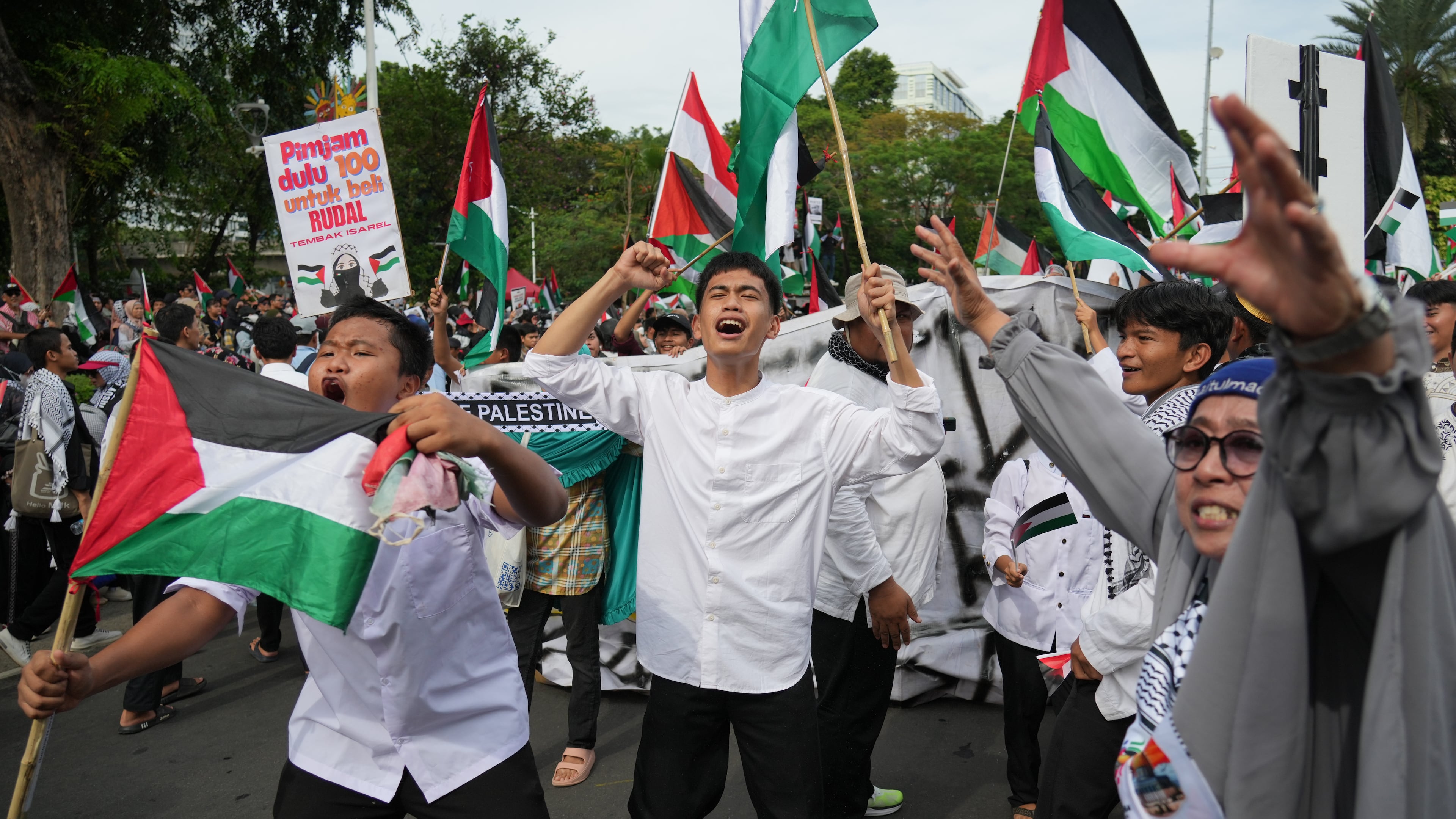 Protesters wave Palestinian flags as they shout slogans during a rally commemorating the second anniversary of the war in Gaza, outside the US Embassy in Jakarta, Indonesia, Tuesday, Oct. 7, 2025. (AP Photo/Achmad Ibrahim)