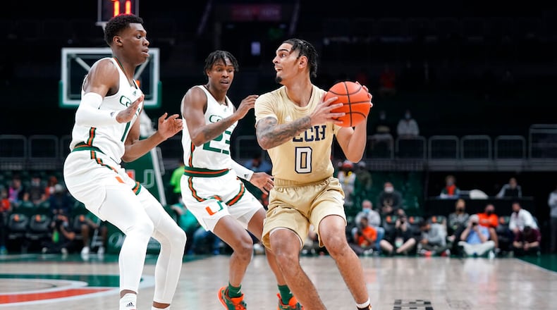 Georgia Tech guard Michael Devoe (0) looks for an open teammate past Miami forward Anthony Walker (1) and guard Kameron McGusty (23) during the first half of an NCAA college basketball game, Wednesday, Feb. 9, 2022, in Coral Gables, Fla. (AP Photo/Wilfredo Lee)