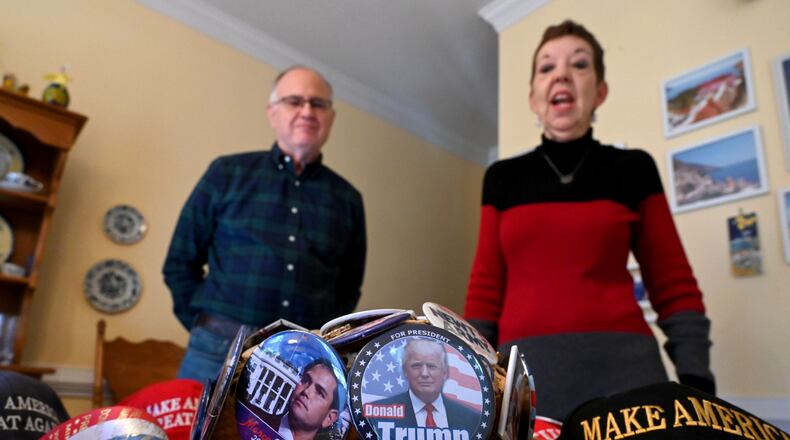Judy Griffin shows her cowboy hat decorated with Republican buttons she has collected over the years as her husband Brian Griffin (left) looks on at their home in Woodstock on Tuesday, January 14, 2025. Judy and Brian Griffin are traveling to Washington D.C. for Donald Trump's second inauguration. (Hyosub Shin / AJC)