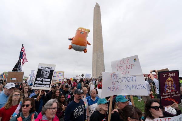 Demonstrators carry signs during the "Hands Off!" protests against President Donald Trump and Elon Musk at the Washington Monument in Washington, Saturday, April 5, 2025. (AP Photo/Jose Luis Magana)