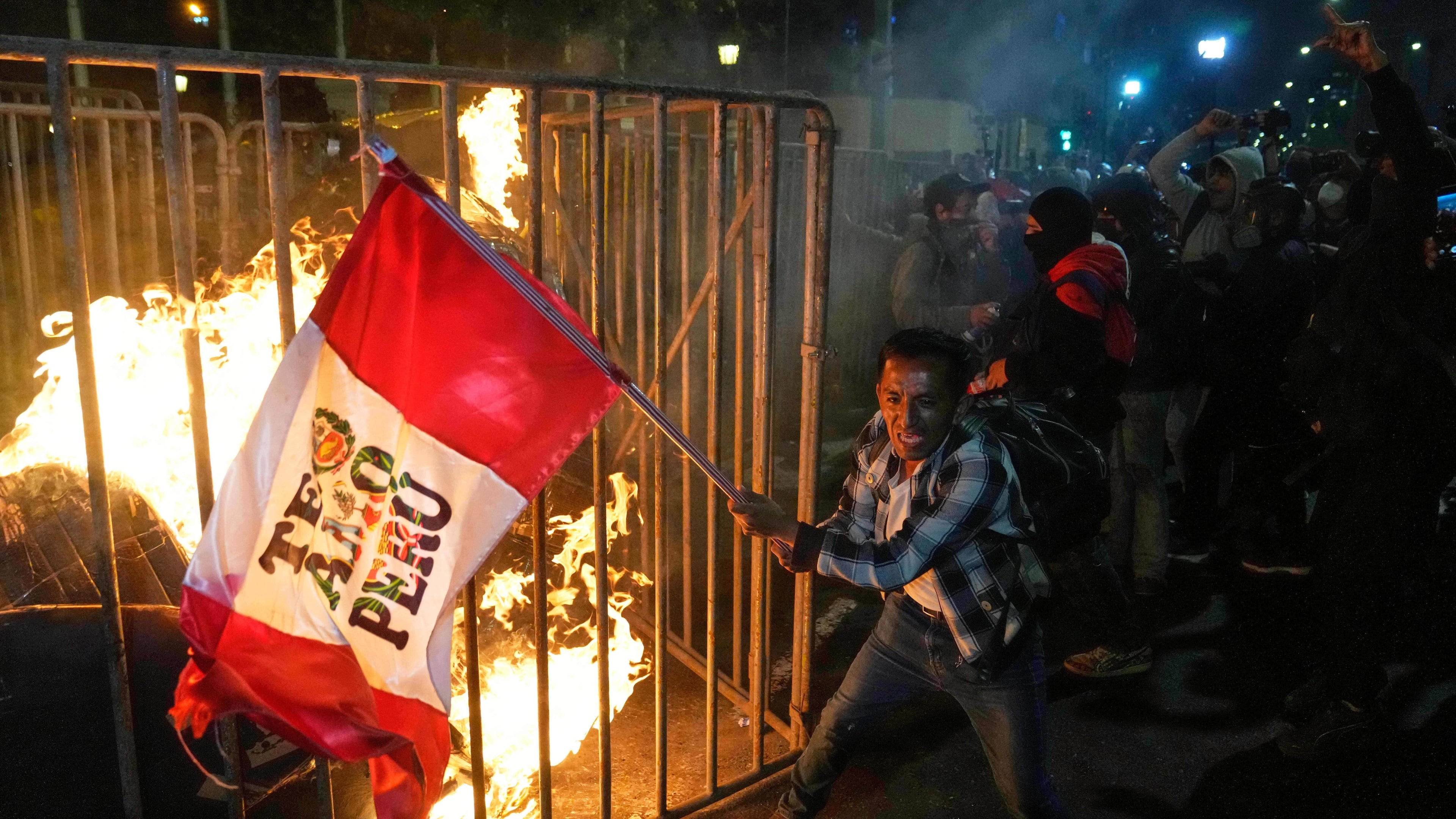 FILE - A demonstrator waves a Peruvian flag as a cardboard doll burns in front of Congress during a protest against new President Jose Jeri in Lima, Peru, Wednesday, Oct. 15, 2025. (AP Photo/Martin Mejia, File)