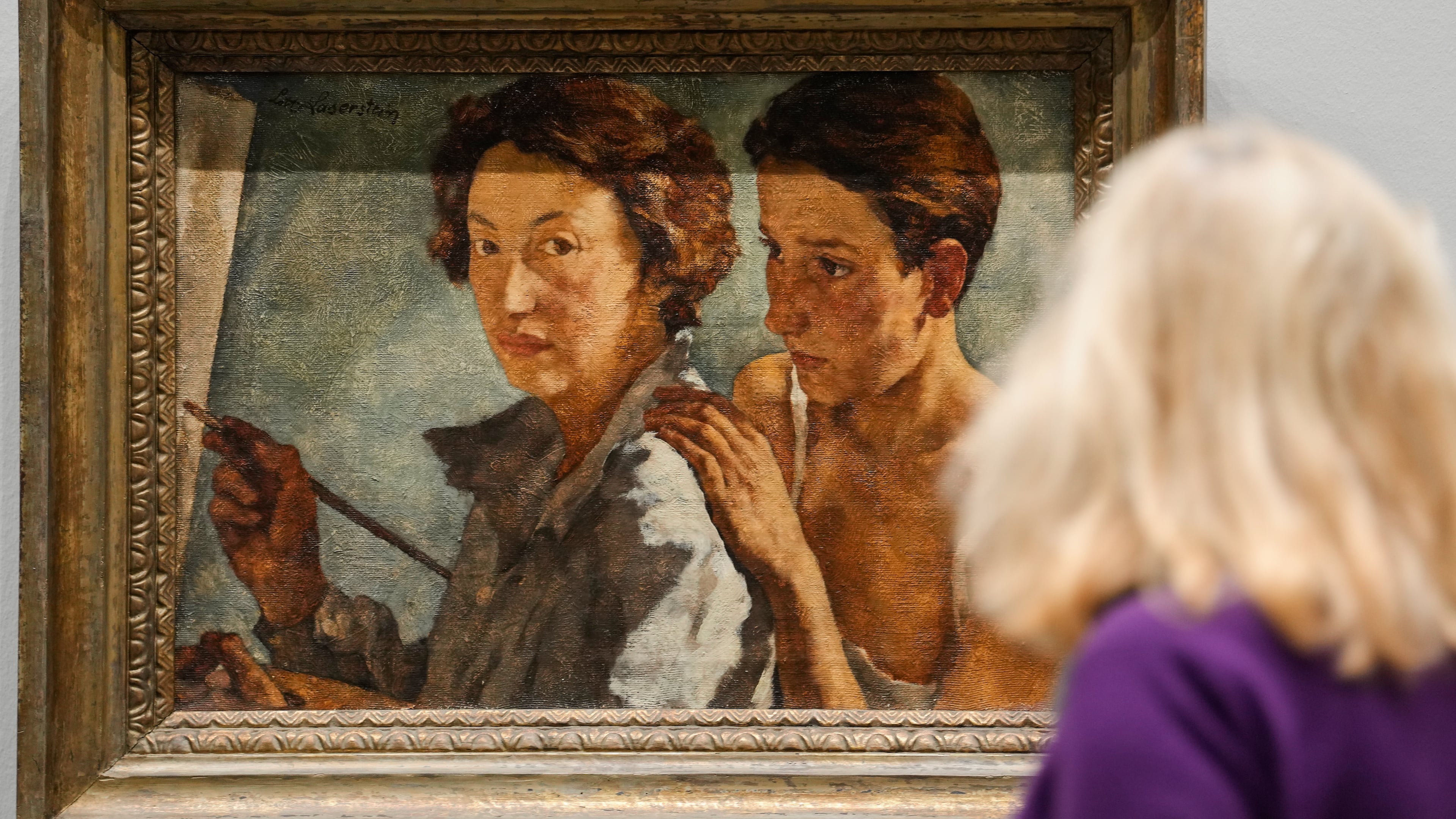 A woman looks at the artwork "I and my model" by artist Lotte Laserstein at the new exhibition "Queer Modernism. 1900 to 1950" at the Kunstsammlung NRW museum in Duesseldorf, Germany, highlighting the contributions of queer artists to modernism. (AP Photo/Martin Meissner)