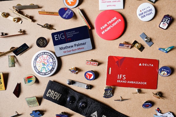 Mathew Palmer, a former Delta Air Lines employee, displays the collection of Delta pins he accumulated during his time with the company at his home in Atlanta on Thursday, Oct. 9, 2025. Some of those feature his prior anti-union advocacy among Delta. He acknowledges the advantage union protection might have offered him, after he was terminated for a social media post regarding Charlie Kirk's killing. (Natrice Miller/AJC) 