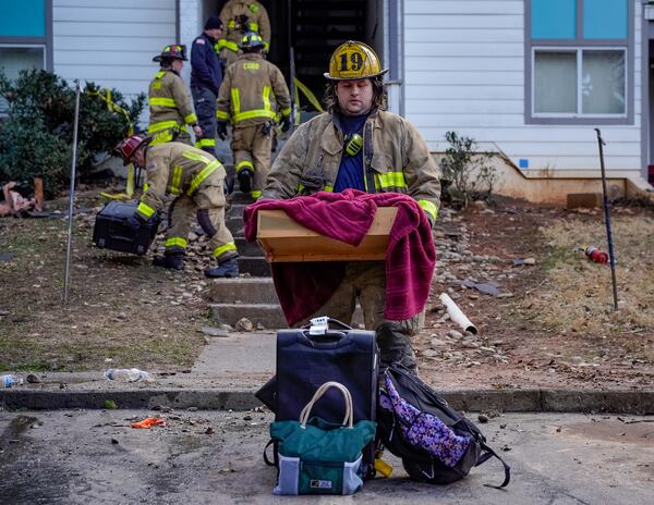Cobb County firefighters carry residents' belongings out of a burned apartment building in the Concord Crossing complex. Some 30 people were left homeless. (Ben Hendren for the AJC)