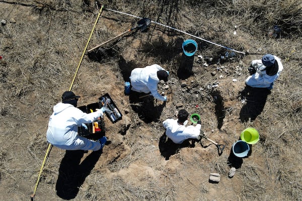 FILE - Forensic technicians excavate a field on a plot of land referred to as a cartel "extermination site" where burned human remains are buried, on the outskirts of Nuevo Laredo, Mexico, Feb. 8, 2022. (AP Photo/Marco Ugarte, File)