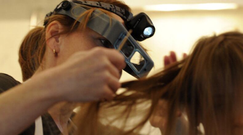 Cathy Tarala, of The Lice Squad, inspects an 8-year-old girl’s hair, applying special enzymes and using a fine stainless steel comb to clean the tiny insects and their eggs from her hair. (Credit: Tony Bock / Toronto Star via Getty Images)