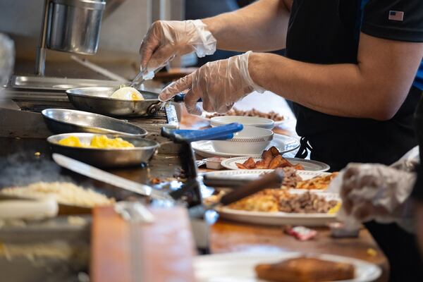 Cooks work the grill at the Waffle House on Peachtree Road in Brookhaven on Friday, Aug. 14, 2026. (Ben Gray for the AJC)