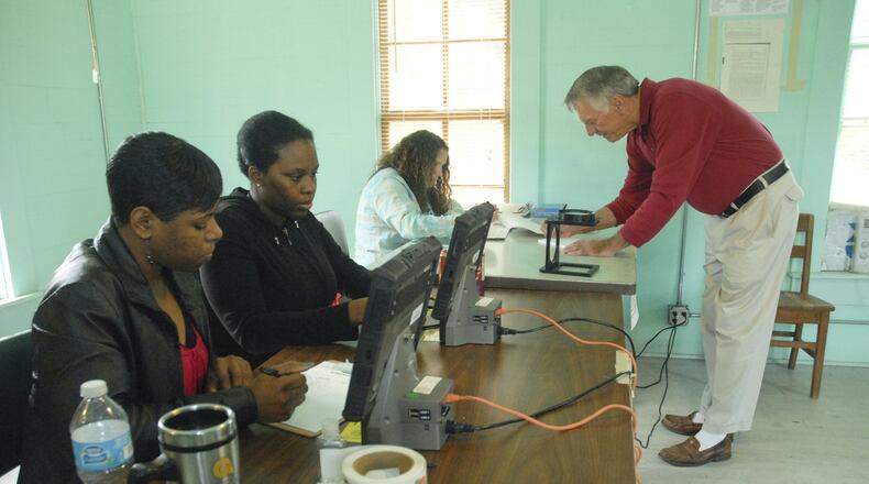 Poll workers, from left, Markeia White, Lawonda Davis and Alyssa Watson help voter Leron Bush, right, sign in before voting at the Hoggards Mill Precinct in Baker County, Ga., Tuesday, Nov. 4, 2013.