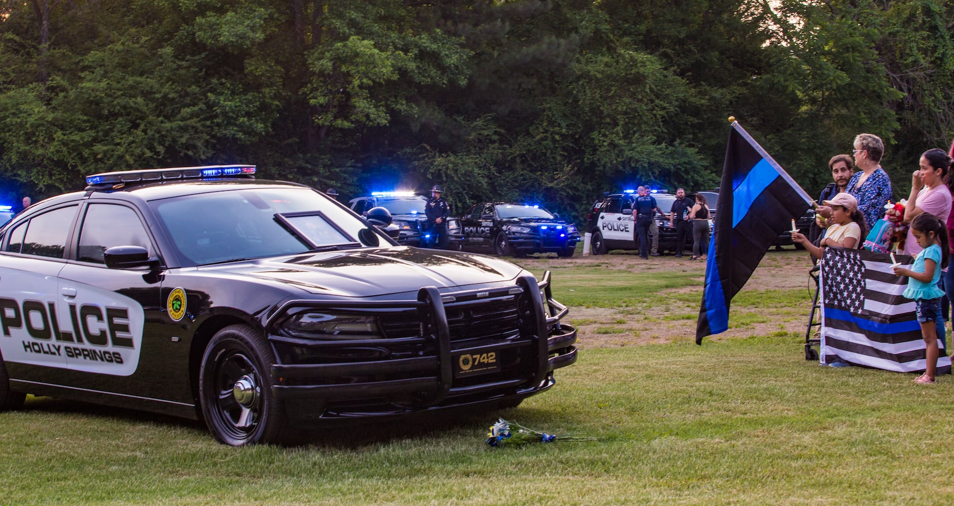 Members of the Holly Springs community and neighboring police departments gather at Barrett Park for a candlelight vigil for Police Officer Joe Burson on Friday, June 18, 2021 after he was killed during a traffic stop earlier this week.  (Jenni Girtman for The Atlanta Journal-Constitution)