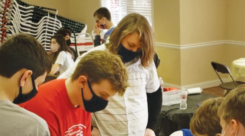Daniel McCorbie (center) demonstrates a prosthetic hand he produced as a member of the Sequoyah High robotics team.