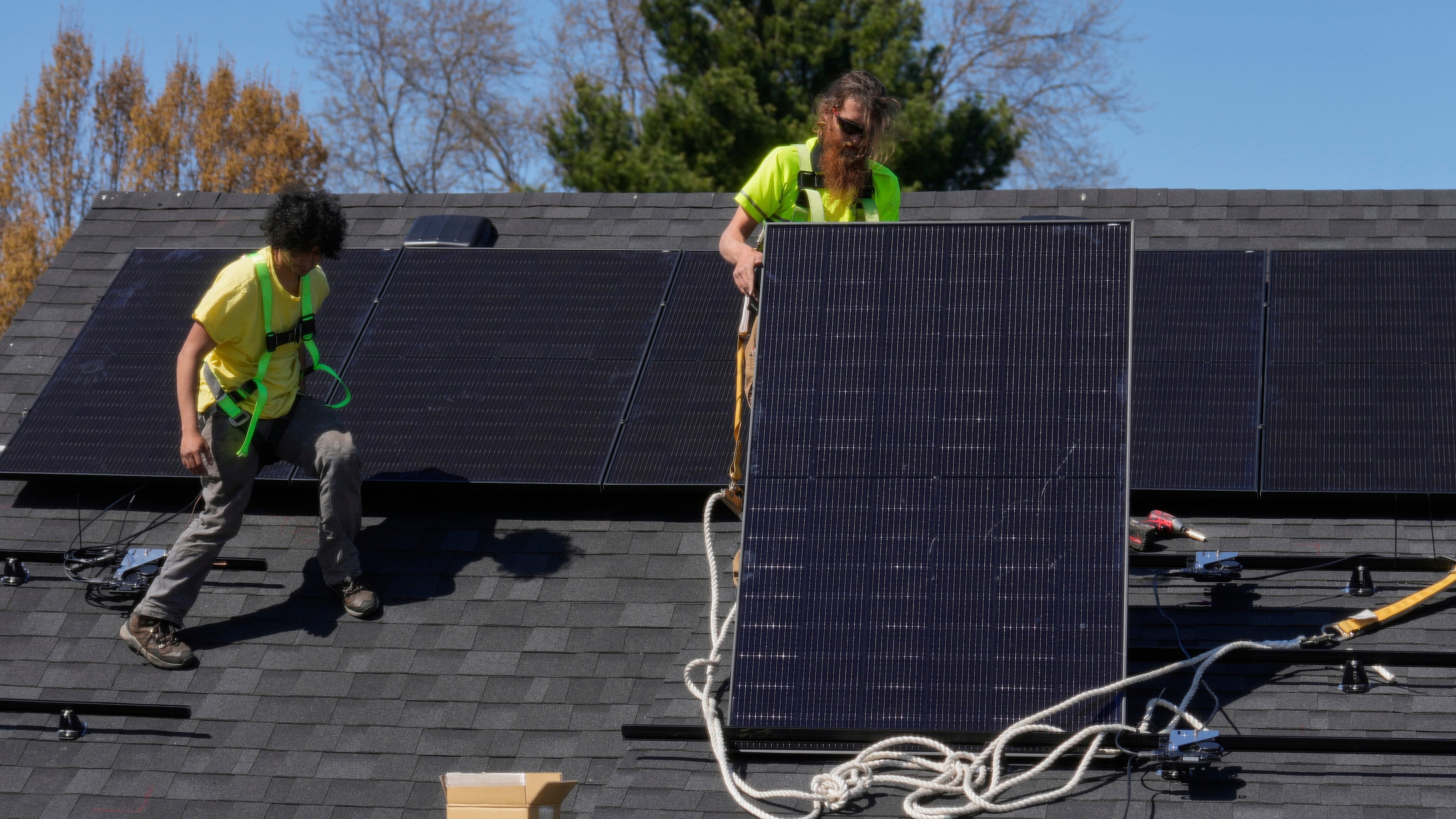 FILE - Brayan Santos, left, and Theodore Tanczuk, right, of solar installer YellowLite, put solar panels on the roof of a home in Lakewood, Ohio, April 16, 2025. (AP Photo/Sue Ogrocki, File)