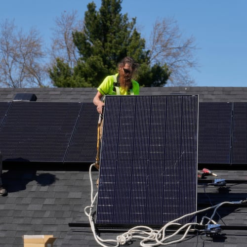 FILE - Brayan Santos, left, and Theodore Tanczuk, right, of solar installer YellowLite, put solar panels on the roof of a home in Lakewood, Ohio, April 16, 2025. (AP Photo/Sue Ogrocki, File)