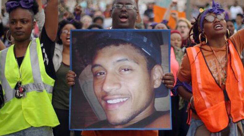 Protesters, including Brandan Marshall holding a photo of Anthony Hill, take to the streets of downtown Decatur to protest Hill's shooting death on March 9, 2015. BEN GRAY / BGRAY@AJC.COM