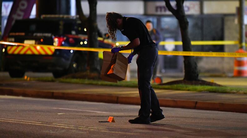 Officers gather evidence after a shooting in the parking lot of a gas station on Pryor Road on Sunday.