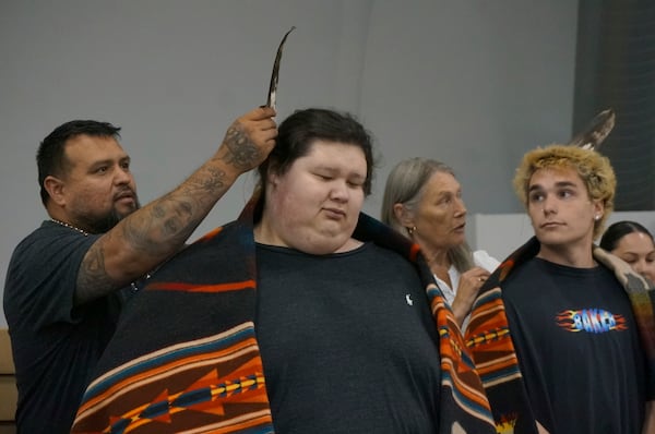 Relatives place bald eagle feathers on the heads of new high school graduates, as a mark of accomplishment and as reverence to the bird they hold sacred, at a ceremony at the Prairie Island Indian Community in Minnesota on Wednesday, July 9, 2025. (AP Photo/Giovanna Dell'Orto)