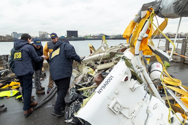 In this image released by the National Transportation Safety Board, an NTSB team surveys the wreckage, April 11, 2025, in Jersey City, N.J., recovered from the Bell 206 L-4 helicopter that crashed into Hudson River on April 10, between New York City and New Jersey. (NTSB via AP)
