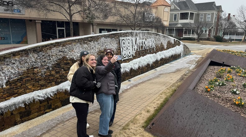 Students at the edge of Mercer University’s Macon campus snap selfies in front of an iced-over fountain. (Joe Kovac Jr. / AJC)