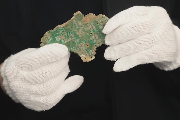 A Thai official shows a sample of illegally imported electronic waste from the United States which they said they seized at Bangkok Port during a press conference in Bangkok, Thailand, Wednesday, May 14, 2025. (AP Photo/Sakchai Lalit)