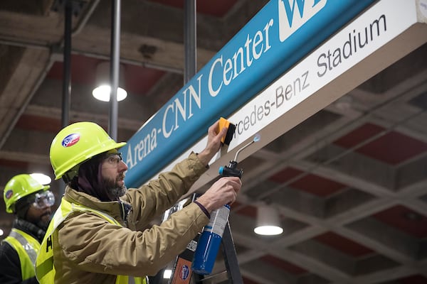 This 2019 photo shows workers updating a MARTA sign to include Mercedes-Benz Stadium. Officials are finally changing the actual name of the station. (Alyssa Pointer/AJC)