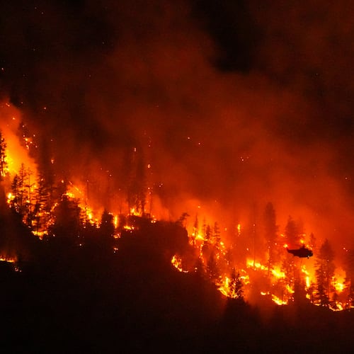 FILE - A helicopter conducting night operations prepares to drop water on the Quilpituk Creek wildfire burning on the west side of Okanagan Lake near Fintry, British Columbia, Aug. 3, 2026. (Darryl Dyck/The Canadian Press via AP, File)