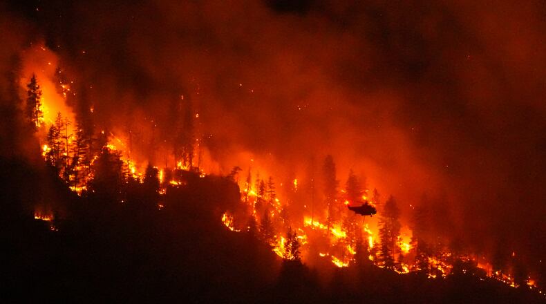 FILE - A helicopter conducting night operations prepares to drop water on the Quilpituk Creek wildfire burning on the west side of Okanagan Lake near Fintry, British Columbia, Aug. 3, 2026. (Darryl Dyck/The Canadian Press via AP, File)