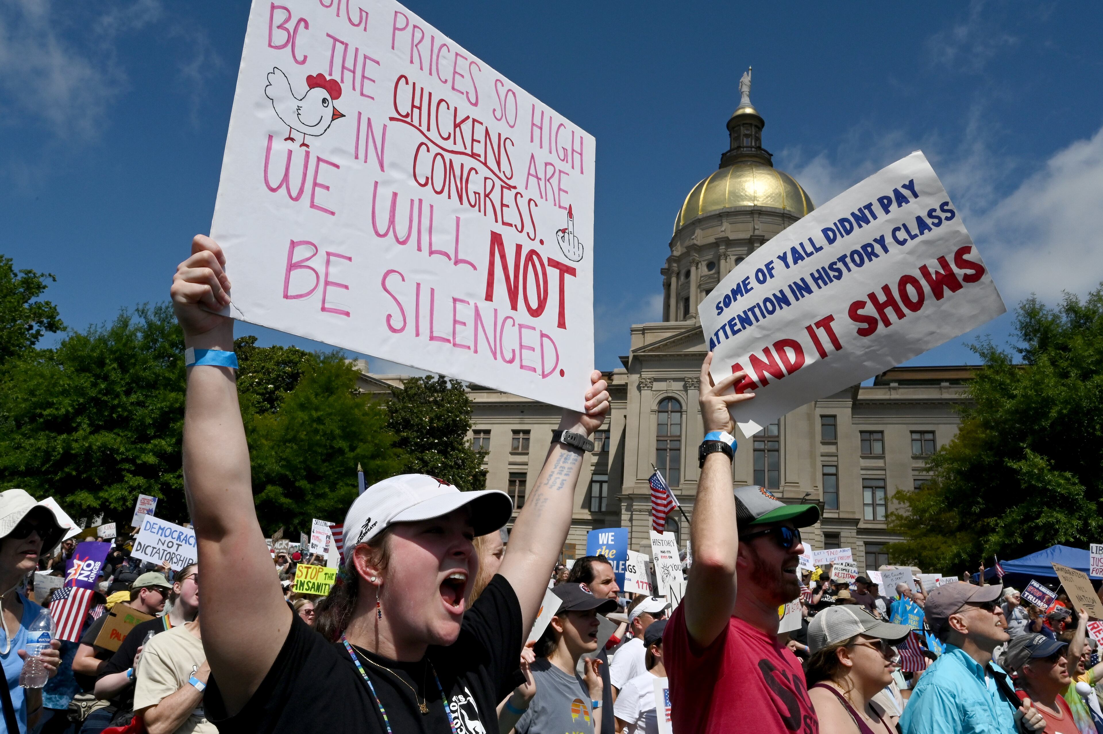 Demonstrators hold signs at Liberty Plaza, near the Georgia Capitol, for a "No Kings" protest to oppose Trump’s immigration policies, Saturday, June 14, 2025, in Atlanta. (Hyosub Shin / AJC)