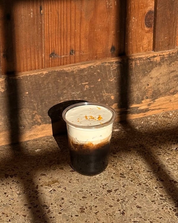 A cold brew coffee drink sits in a brightly lit area with shadows from window panes cast over the frame