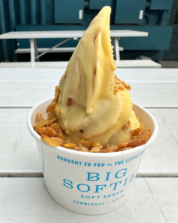 A cup of soft serve ice cream in a white cup that says Big Softie