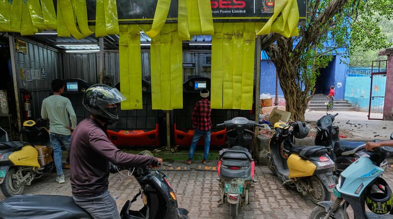 Delivery workers and drivers arrive at a battery-swapping station for electric vehicles in New Delhi, India, Monday, July 13, 2026. (AP Photo/Manish Swarup)
