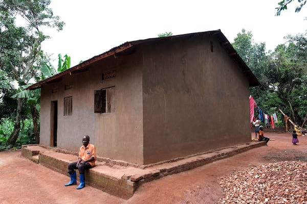 Simon Tigawalana rests in front of his house with clay-based earthen floors by EarthEnable on May 16, 2025, in Jinja, Uganda. (AP Photo/Hajarah Nalwadda)