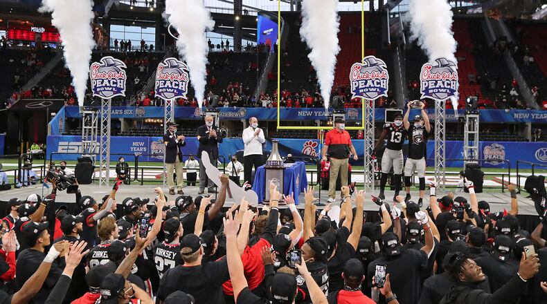 010121 ATLANTA: Georgia head coach Kirby Smart (from left), defensive player of the game Azeez Ojulari and quarterback JT Daniels take the stage to celebrate beating Cincinnati 24-21 in the NCAA college football Peach Bowl game on Friday, Jan. 1, 2021, in Atlanta. Curtis Compton / Curtis.Compton@ajc.com”